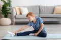 Cute redhead boy stretching on fitness mat at home Royalty Free Stock Photo