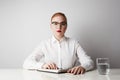 Cute redhead business woman working at the table over empty white background. Royalty Free Stock Photo