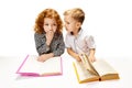 Cute redhead, curly girl sitting at desk with little boy who quietly tells her secret. Child study and learn for