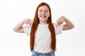 Cute redhead little girl with freckles showing promotional text, pointing down at banner and smiling toothy. Ginger Royalty Free Stock Photo