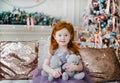 Cute redhead little girl with two small teddy bears in hands on Christmas background Royalty Free Stock Photo