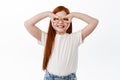 Cute redhead little girl wishes to become superhero, making hero mask with hands on eyes and smiling toothy, having fun