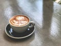 Cute rose latte art coffee in black and white cup on the cement background