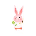 Cute rosy easter bunny paints egg with brush isolated on white background