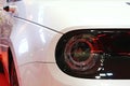 Cute round headlight of battery electric supermini car Honda e, camera holders instead of rearview mirrors visible in background.