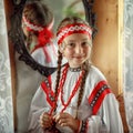 Cute Russian girl in a traditional costume on the background of a mirror