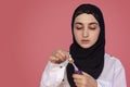 Cute 20s female putting lipstick with a brush. Beautiful Persian woman in hijab doing make-up applying lipstick on her lips Royalty Free Stock Photo