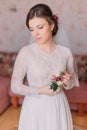 Cute sad bride at home in white wedding dress, preparations concept. Portrait of tender depressed girl in gown