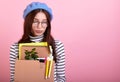 Cute sad lady in a stylish beret hat, with a cardboard box in her hands on a pink background Royalty Free Stock Photo