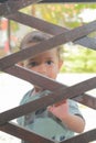Sad curious toddler boy standing behind fence Royalty Free Stock Photo