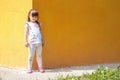 Cute little girl standing near the yellow wall