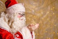 Cute santa claus in glasses on a wall background with a bright garland bokeh Royalty Free Stock Photo