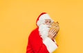 Cute Santa Claus hugging a toy deer on a yellow background. Christmas and New Year concept. Santa and a plush toy Royalty Free Stock Photo