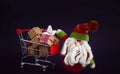 Cute Santa Claus toy, sitting near with red shopping cart. Christmas sale or New Year concept, isolated on black background Royalty Free Stock Photo
