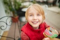 Cute school age boy eating funny colorful donut in a street cafe while walking in the city center Royalty Free Stock Photo