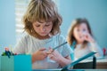 Cute school boy drawing in classroom. Pretty stylish schoolkid studying homework math during lesson at classroom Royalty Free Stock Photo