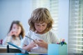 Cute school boy drawing in classroom. Pretty stylish schoolkid studying homework math during lesson at classroom Royalty Free Stock Photo