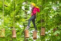 Cute school child boy enjoying a sunny day in a climbing adventure activity park. Children summer activities. Roping