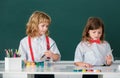 Cute school friends kids drawing and painting at school. Friendly boy an girl funny pupils draw on blackboard background