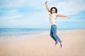 School girl jumping on beach near sea, space for text. Summer holidays Royalty Free Stock Photo