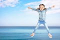 School girl jumping near sea, space for text. Summer holidays Royalty Free Stock Photo