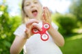 Cute school girl playing with fidget spinner on the playground. Popular stress-relieving toy for school kids and adults. Royalty Free Stock Photo