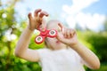 Cute school girl playing with fidget spinner on the playground. Popular stress-relieving toy for school kids and adults. Royalty Free Stock Photo