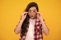 Cute school girl wearing glasses on yellow studio background, smart clever schooler girl in eyeglasses. Nerd student Royalty Free Stock Photo