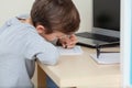 Cute school pupil kid boy studying at home writing notes sitting at desk. Schoolboy writes homework with his left hand Royalty Free Stock Photo