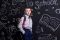 Cute schoolboy standing before the chalkboard as a background with a backpack on his back. Landscape picture