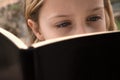Cute schoolgirl reading the book in the open air, close up Royalty Free Stock Photo