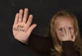 Cute schoolgirl scared sad asking for help showing hands with stop bullying text written on her palm