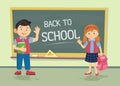 Cute little schoolgirl and schoolboy wearing uniform with backpacks standing near blackboard with copy space isolated on Royalty Free Stock Photo