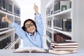 Cute schoolgirl showing thumbs up in the library