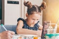 A cute schoolgirl is sitting at a table and watching an online drawing lesson. The child is at home due to the COVID-19 quarantine Royalty Free Stock Photo