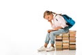 cute schoolkid sitting on books and reading on white.