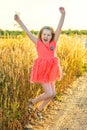 Cute screaming little girl in pink dress jump outdor in field in sunset. Royalty Free Stock Photo