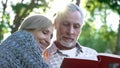 Cute senior couple viewing photoalbum, remembering funny moments of life