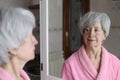 Cute senior woman looking at her reflection in the bathroom Royalty Free Stock Photo