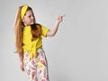 Cute serious little red-haired girl wearing summer fashion clothes pointing her finger to the side on the corner against Royalty Free Stock Photo