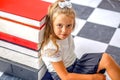 Cute serious schoolgirl sitting near a stack of books Royalty Free Stock Photo