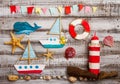 Set of kids handcrafted boats, fish, nautical attributes and more on rough vintage wooden background top view