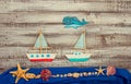 Set of kids handcrafted boats, fish, nautical attributes and more on rough vintage wooden background top view Royalty Free Stock Photo