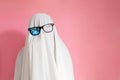 Cute sheet ghost costume with broken sunglasses on a pink background. Halloween party carnival concept Royalty Free Stock Photo