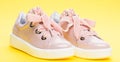 Cute shoes on yellow background. Footwear for girls or women decorated with pearl beads. Pair of pale pink female