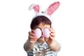 Cute short haired smiling little child with blurred face wearing bunny ears on Easter day with two painted pink eggs in hands Royalty Free Stock Photo