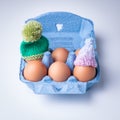 Cute shot of some eggs with small knitted hats on them on a white surface