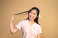 Cute Shy Asian Woman smile and play her hair in orange brown background at outdoor field in sunlight environment Royalty Free Stock Photo