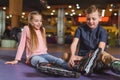 cute siblings in roller skates resting after skating Royalty Free Stock Photo