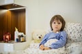 Cute sick child, boy, staying in bed, playing with teddy bear Royalty Free Stock Photo